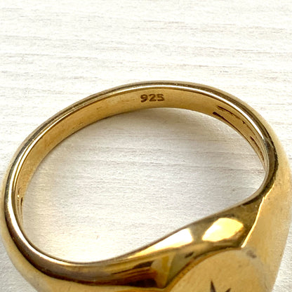 A gold-plated silver ring featuring an oval signet with a single clear stone sparkling at the centre. 楕円のシグネットにクリアストーンが一粒きらりと輝く金メッキされたシルバーリング。 