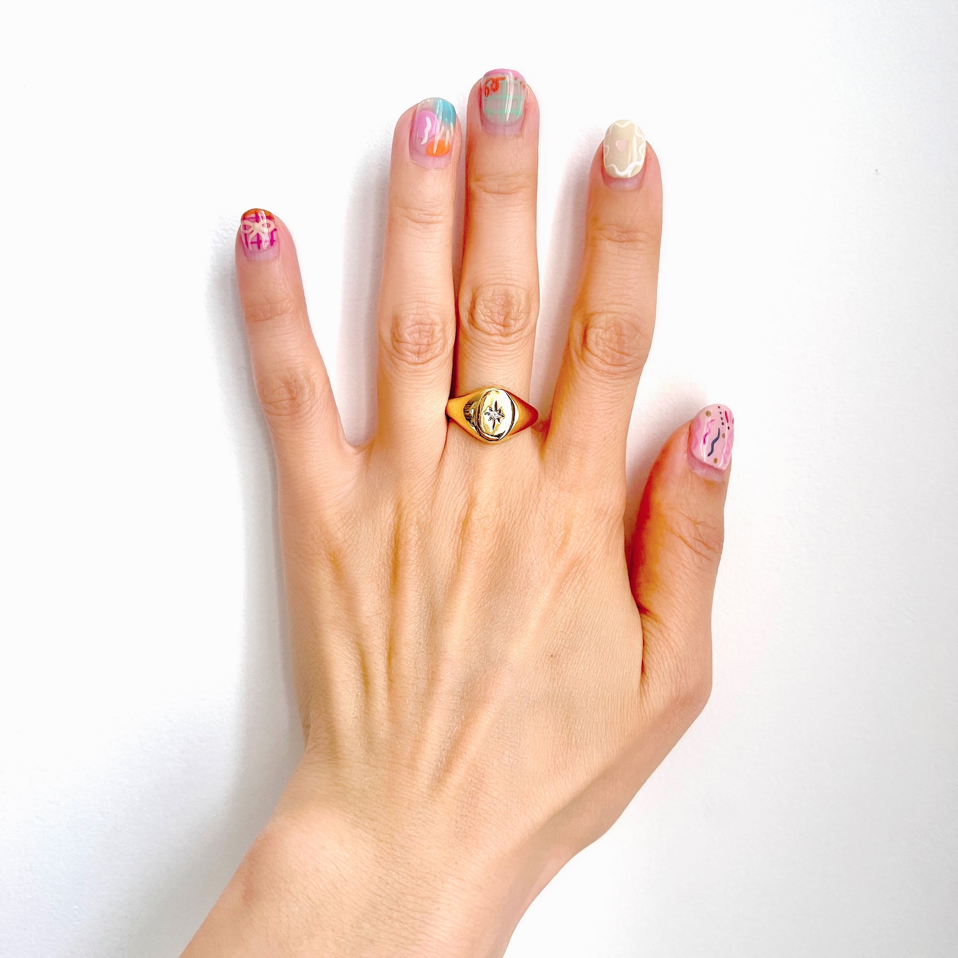 A gold-plated silver ring featuring an oval signet with a single clear stone sparkling at the centre. 楕円のシグネットにクリアストーンが一粒きらりと輝く金メッキされたシルバーリング。 