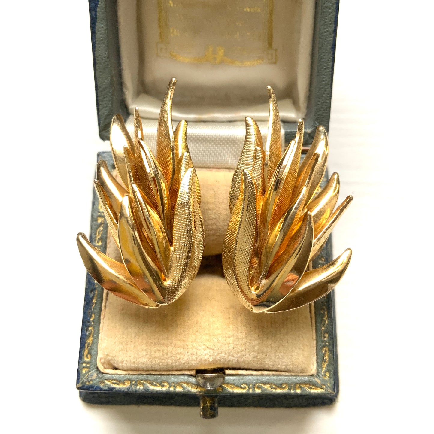 Gold-tone clip-on earrings featuring a sculptural, layered form reminiscent of feathers. 羽のように重なり合う立体的なフォルムが印象的な、ゴールドトーンのクリップイヤリング。