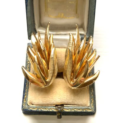 Gold-tone clip-on earrings featuring a sculptural, layered form reminiscent of feathers. 羽のように重なり合う立体的なフォルムが印象的な、ゴールドトーンのクリップイヤリング。