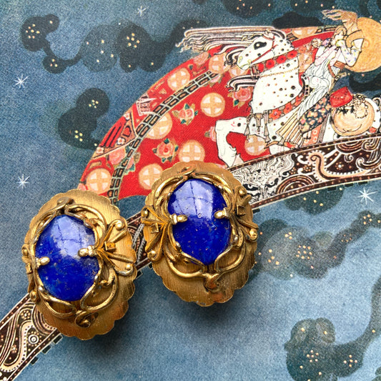 Vibrant blue lapis glass clip-on earrings set in gold-tone metal frames. 鮮やかなブルーのラピスグラスが、ゴールドトーンメタルのフレームに収められたクリップイヤリング。 