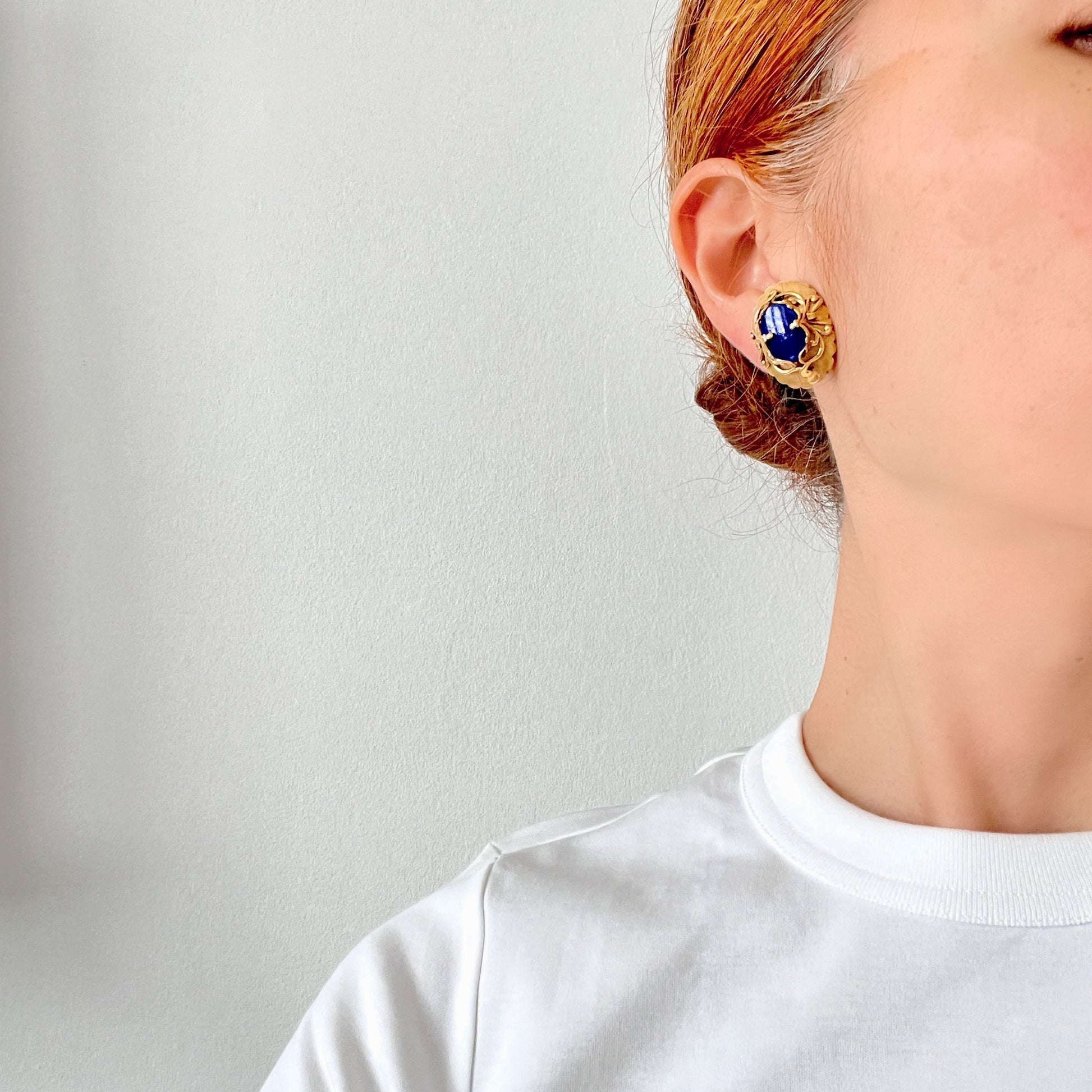 Vibrant blue lapis glass clip-on earrings set in gold-tone metal frames. 鮮やかなブルーのラピスグラスが、ゴールドトーンメタルのフレームに収められたクリップイヤリング。 