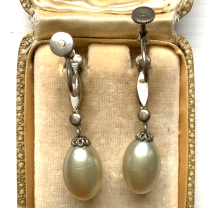  Screw-back earrings featuring oval-shaped glass pearls with a subtle silver-grey tint. うっすらとシルバー/グレーみがかかったオーバル型のグラスパールが揺れるスクリューイヤリング。