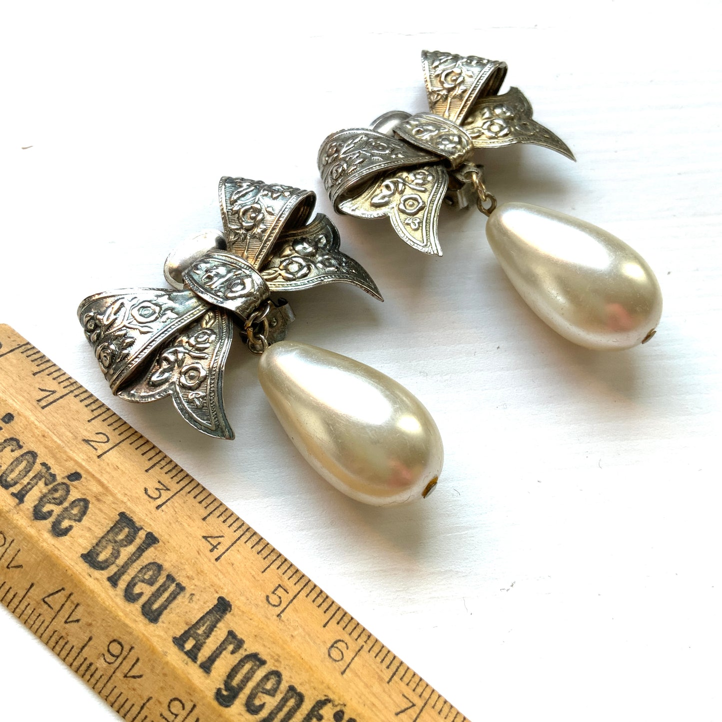 Vintage clip-on earrings featuring a silver-tone bow with large teardrop pearls that gently sway. シルバートーンメタルのリボンに、大きなティアドロップパールが揺れるクリップイヤリング。