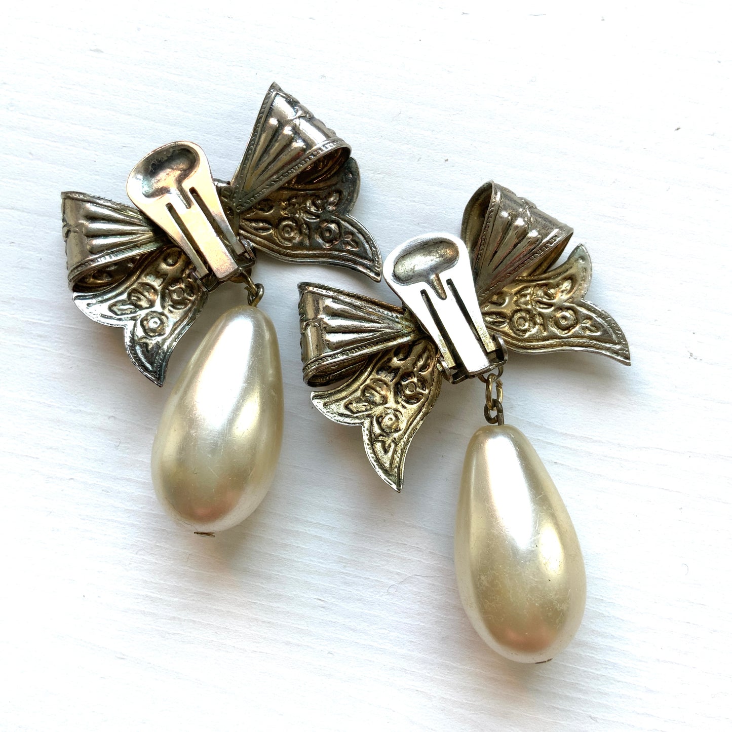 Vintage clip-on earrings featuring a silver-tone bow with large teardrop pearls that gently sway. シルバートーンメタルのリボンに、大きなティアドロップパールが揺れるクリップイヤリング。