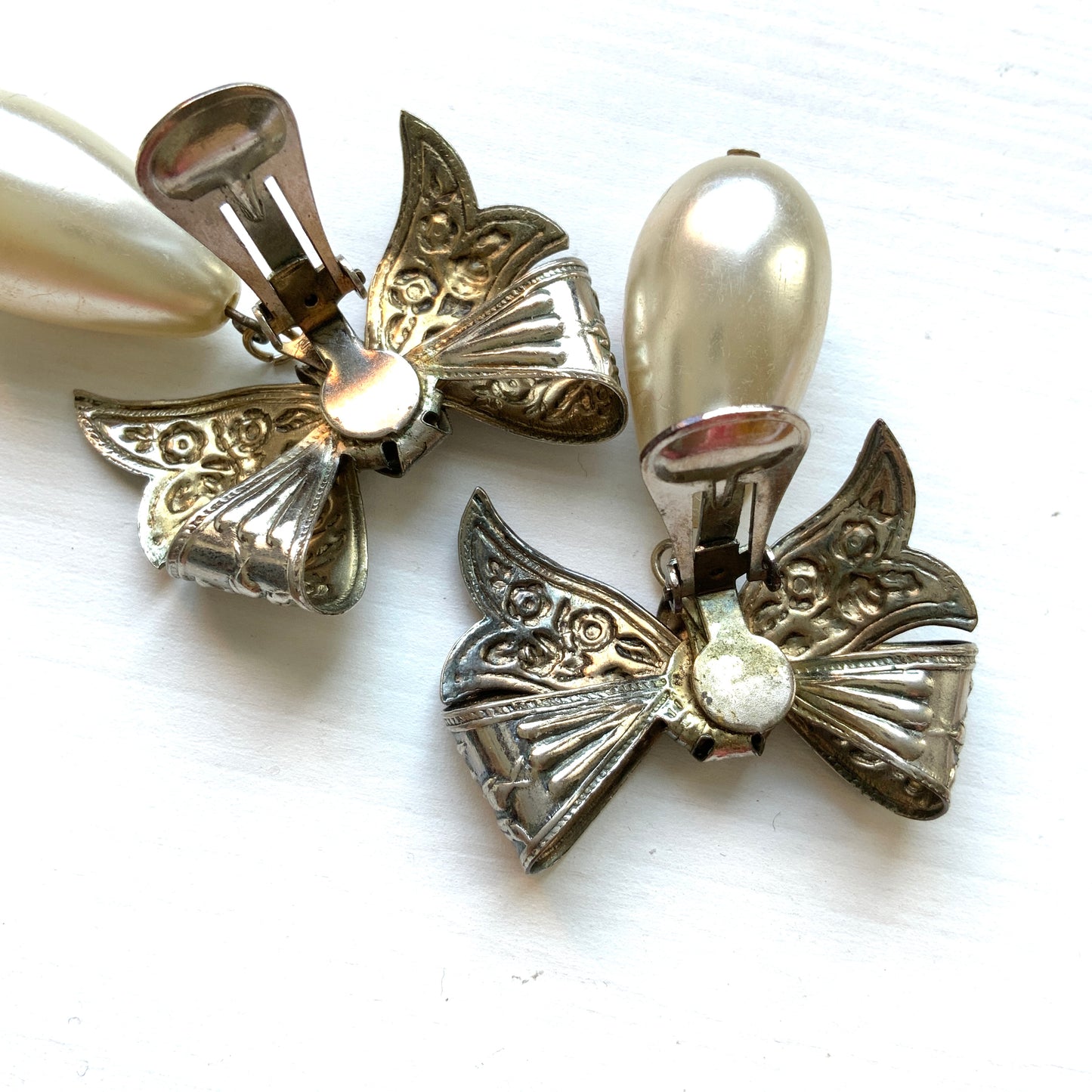 Vintage clip-on earrings featuring a silver-tone bow with large teardrop pearls that gently sway. シルバートーンメタルのリボンに、大きなティアドロップパールが揺れるクリップイヤリング。