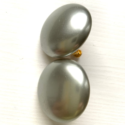 A pair of Napier clip-on earrings featuring large pearl buttons in a deep grey tone. 深みのあるグレーカラーが印象的な、ネイピアの大粒パールボタンのクリップイヤリング。