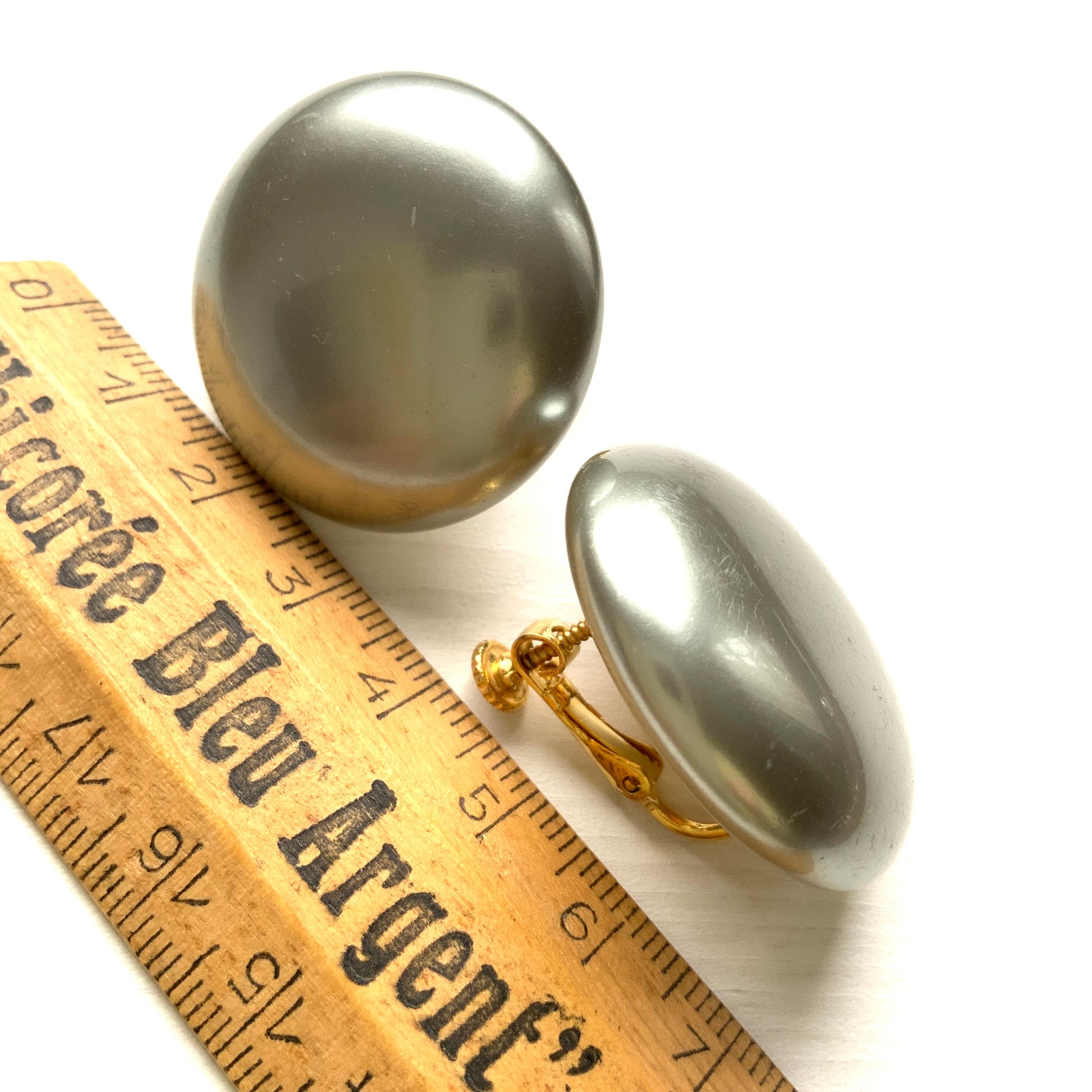 A pair of Napier clip-on earrings featuring large pearl buttons in a deep grey tone. 深みのあるグレーカラーが印象的な、ネイピアの大粒パールボタンのクリップイヤリング。