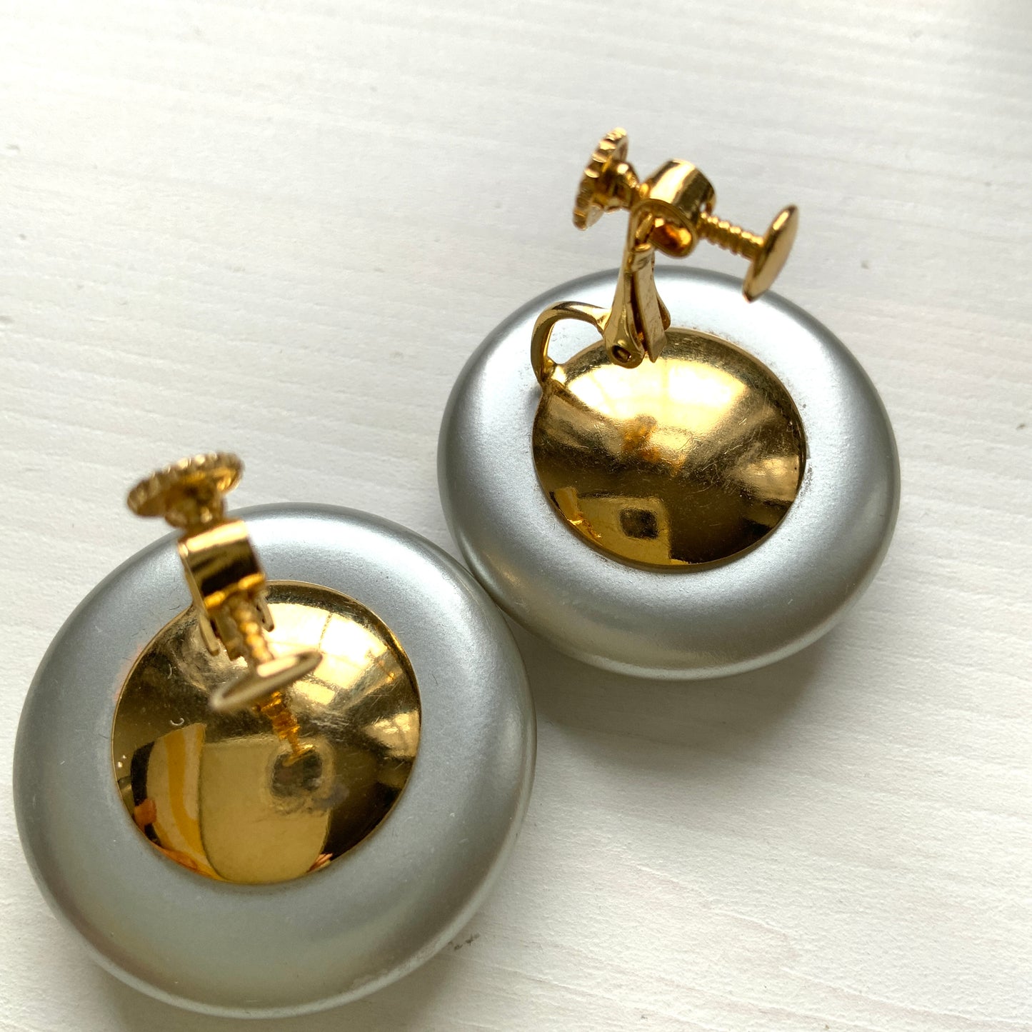 A pair of Napier clip-on earrings featuring large pearl buttons in a deep grey tone. 深みのあるグレーカラーが印象的な、ネイピアの大粒パールボタンのクリップイヤリング。