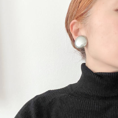 A pair of Napier clip-on earrings featuring large pearl buttons in a deep grey tone. 深みのあるグレーカラーが印象的な、ネイピアの大粒パールボタンのクリップイヤリング。
