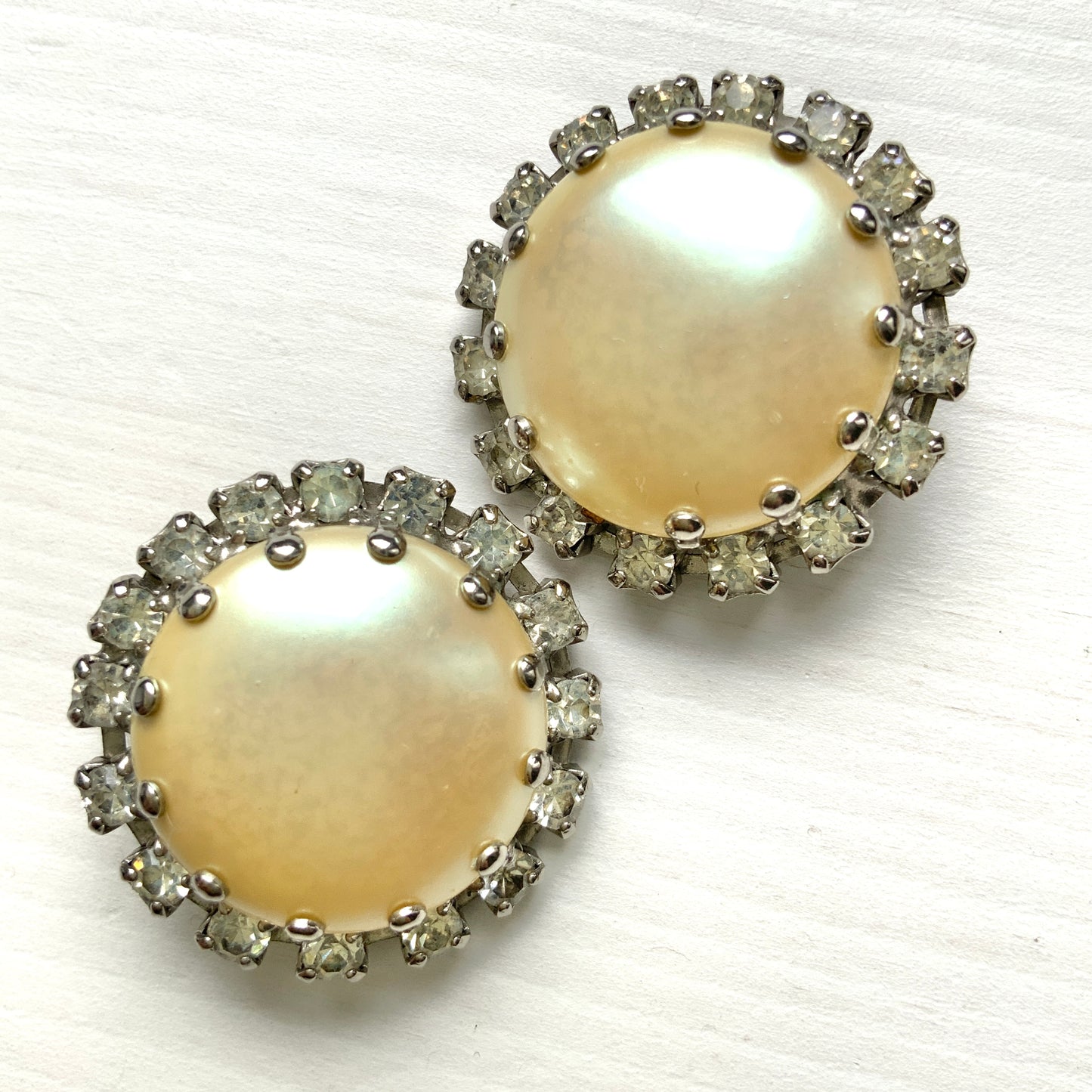 Vintage earrings featuring a flat pearl button surrounded by a halo of clear stones.  フラットなパールボタンの周りを、クリアストーンがぐるりと囲むヴィンテージイヤリング