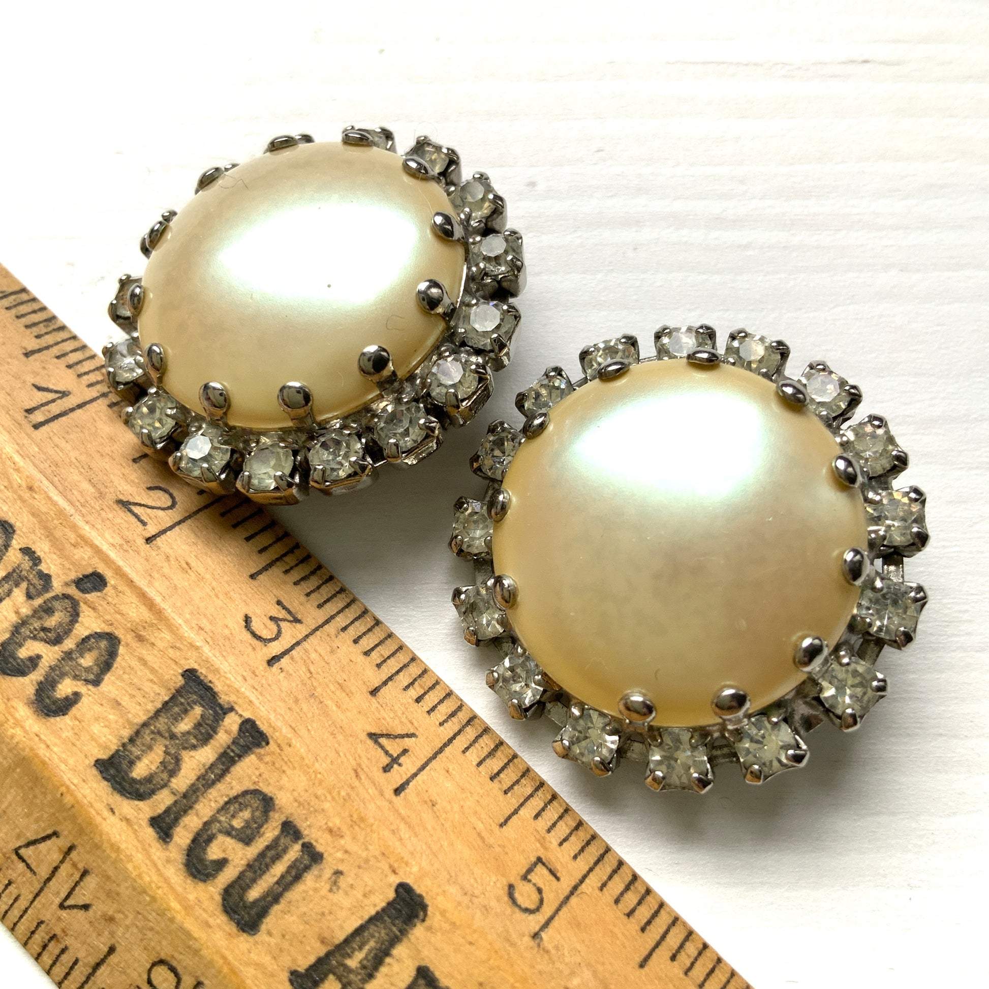 Vintage earrings featuring a flat pearl button surrounded by a halo of clear stones.  フラットなパールボタンの周りを、クリアストーンがぐるりと囲むヴィンテージイヤリング