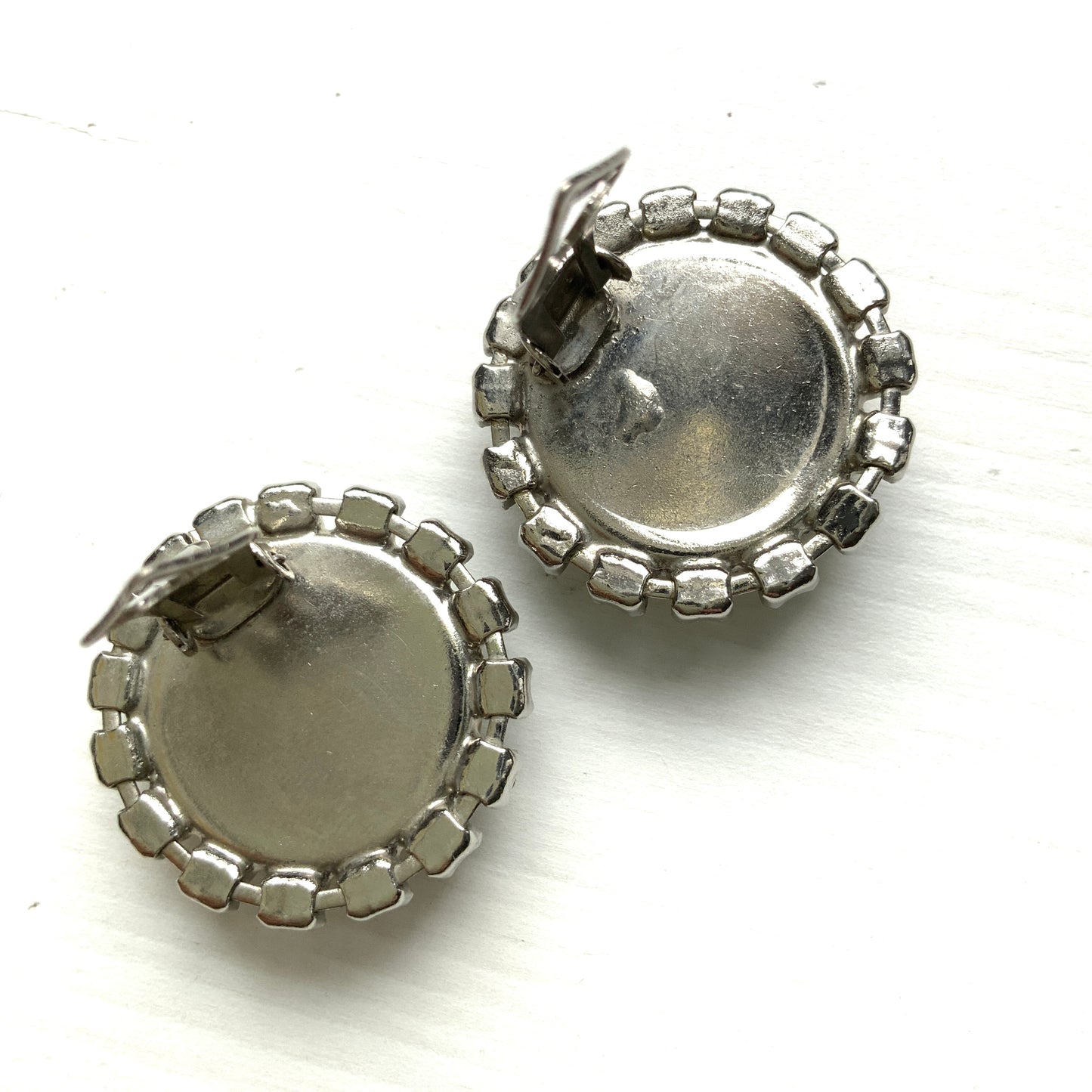 Vintage earrings featuring a flat pearl button surrounded by a halo of clear stones.  フラットなパールボタンの周りを、クリアストーンがぐるりと囲むヴィンテージイヤリング