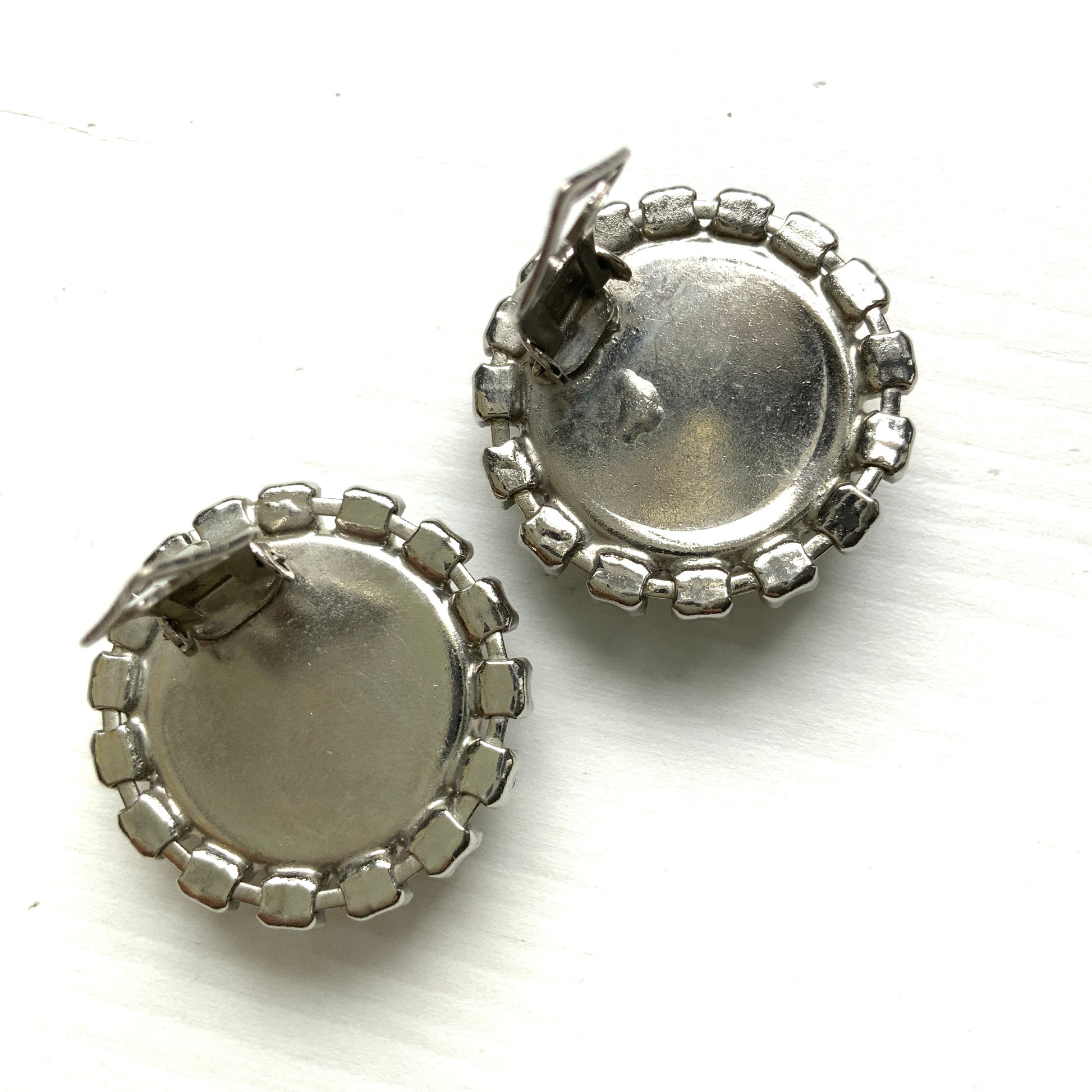Vintage earrings featuring a flat pearl button surrounded by a halo of clear stones.  フラットなパールボタンの周りを、クリアストーンがぐるりと囲むヴィンテージイヤリング