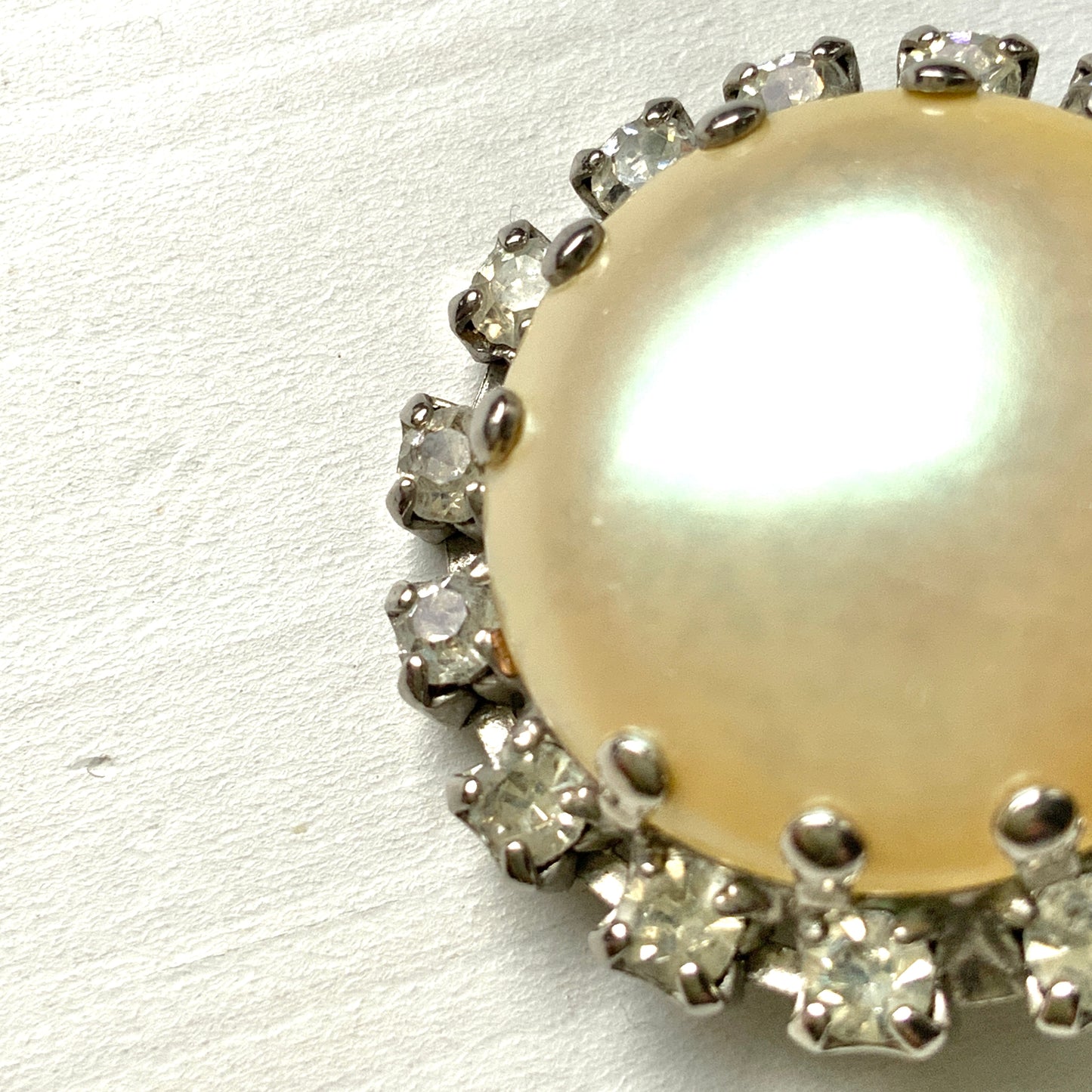 Vintage earrings featuring a flat pearl button surrounded by a halo of clear stones.  フラットなパールボタンの周りを、クリアストーンがぐるりと囲むヴィンテージイヤリング