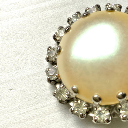 Vintage earrings featuring a flat pearl button surrounded by a halo of clear stones.  フラットなパールボタンの周りを、クリアストーンがぐるりと囲むヴィンテージイヤリング