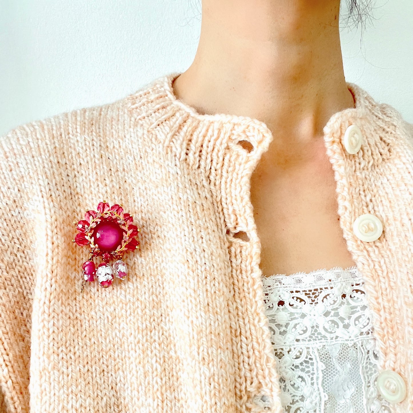 A brooch in soft pink tones, featuring a richly layered design. ピンクのトーンでまとめられた、印象的なデザインのブローチ。