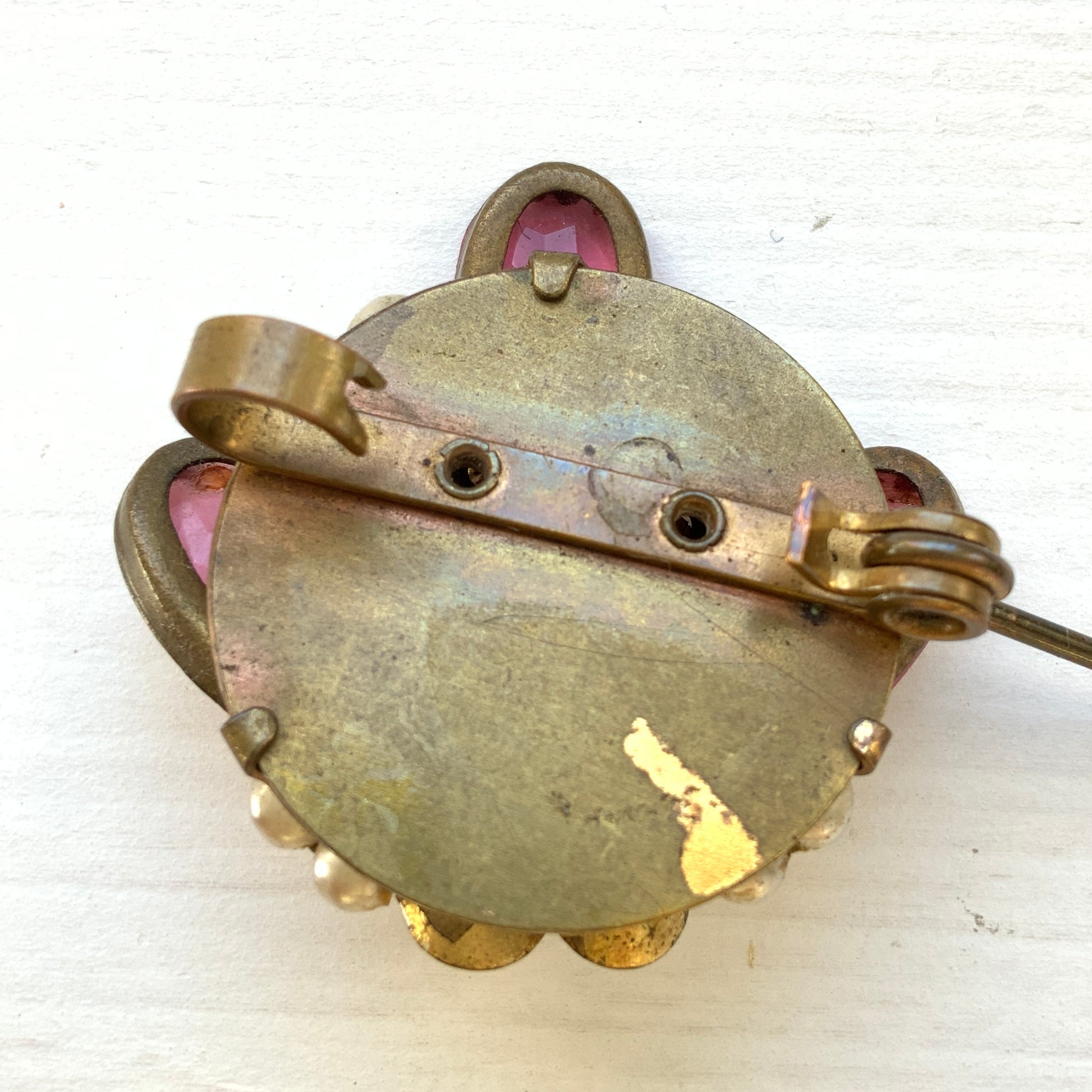 A brooch featuring pink glass, faux pearls and rhinestones. ピンクのガラスとガラスパール、ラインストーンを組み合わせたブローチ。