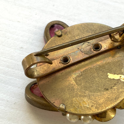 A brooch featuring pink glass, faux pearls and rhinestones. ピンクのガラスとガラスパール、ラインストーンを組み合わせたブローチ。