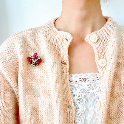 A brooch featuring pink glass, faux pearls and rhinestones. ピンクのガラスとガラスパール、ラインストーンを組み合わせたブローチ。