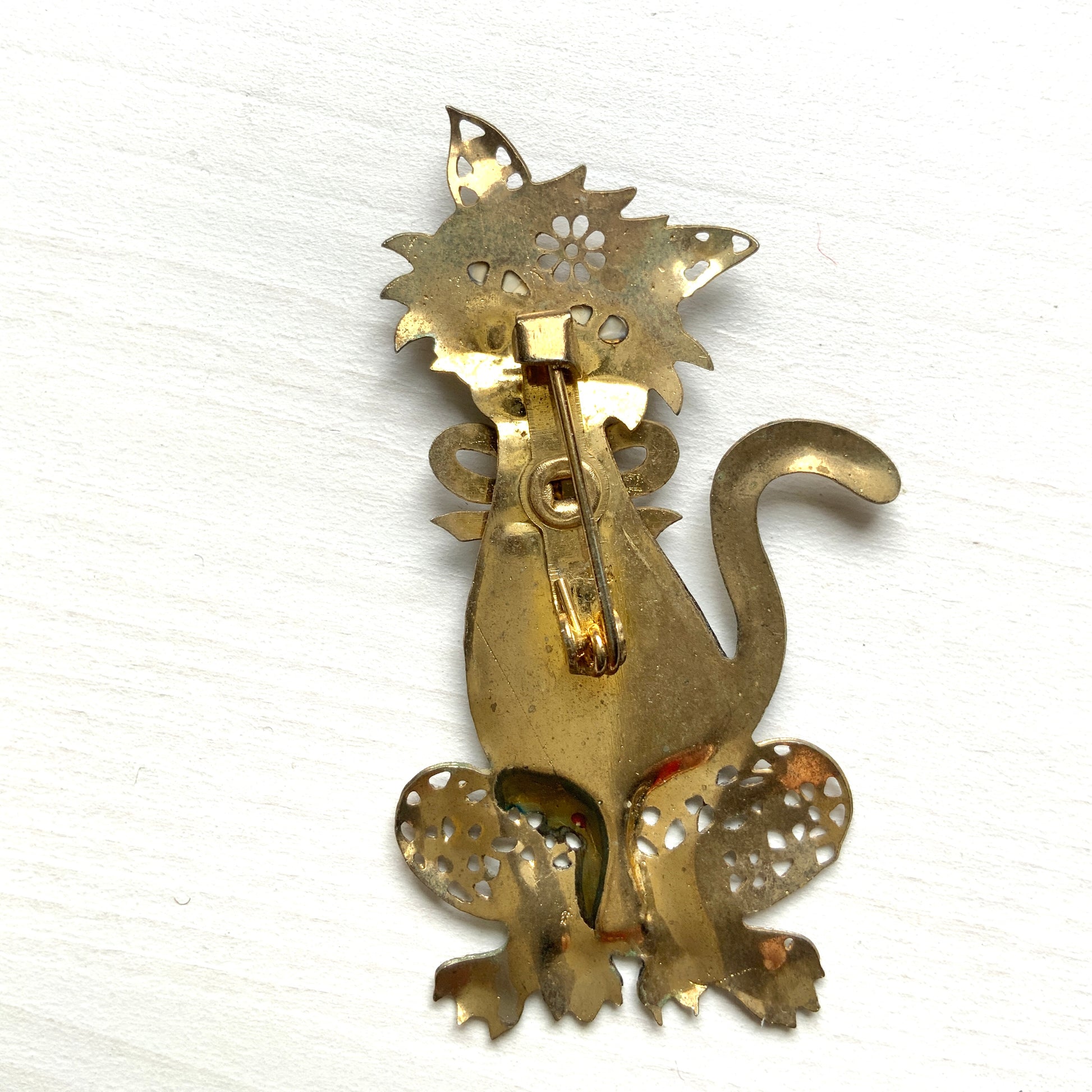 A vintage cat brooch featuring a vibrant rainbow enamel body. レインボーグリッターのボディが印象的な、ヴィンテージのキャットブローチ。