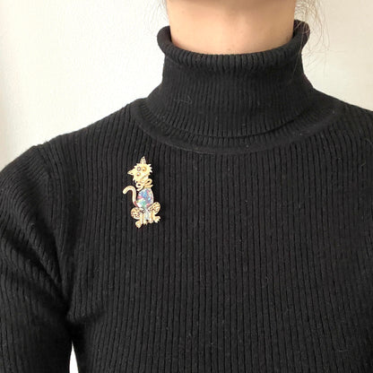 A vintage cat brooch featuring a vibrant rainbow enamel body. レインボーグリッターのボディが印象的な、ヴィンテージのキャットブローチ。