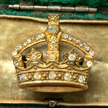 A gold-tone metal crown brooch adorned with clear rhinestones. ゴールドトーンメタルのクラウンに、クリアラインストーンがあしらわれたブローチ。 
