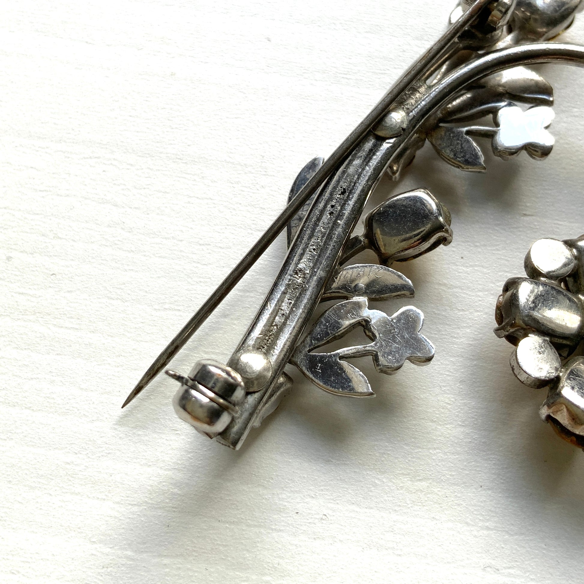 A vintage brooch featuring a large amber glass flower, accented with oval amber glass stones and clusters of small clear rhinestone flowers. アンバーグラスの大輪の花に、同じくアンバーのオーバルグラスと、クリアラインストーンの小さな花々が添えられたブローチ。