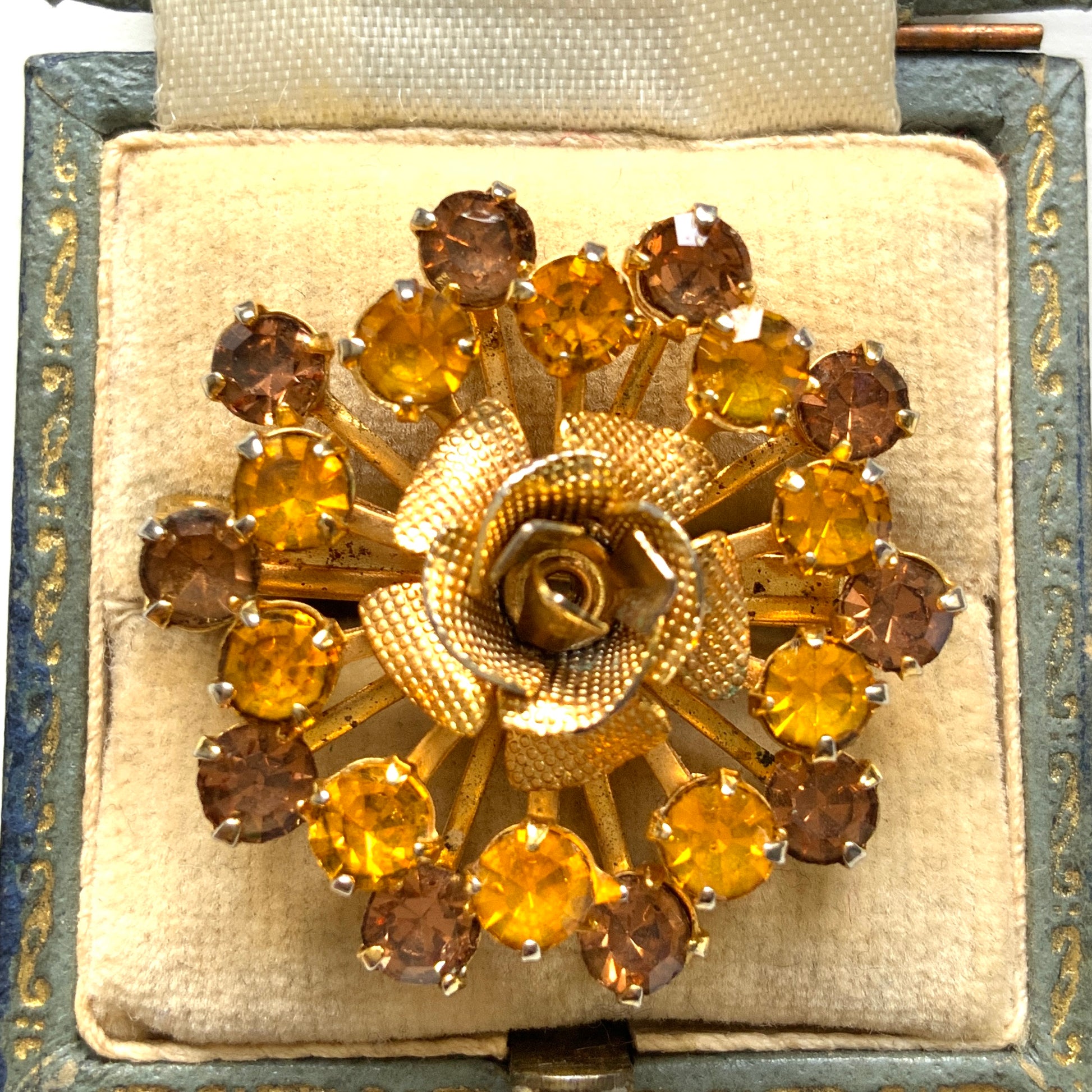 A vintage brooch featuring a small gold-tone rose, with two-tone amber rhinestones sparkling out like a burst of light. ゴールドトーンの小さなバラから２トーンのアンバーラインストーンがスパークしているようなブローチ。