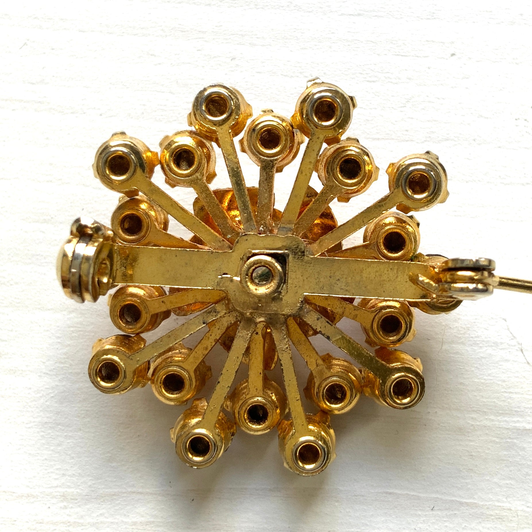 A vintage brooch featuring a small gold-tone rose, with two-tone amber rhinestones sparkling out like a burst of light. ゴールドトーンの小さなバラから２トーンのアンバーラインストーンがスパークしているようなブローチ。