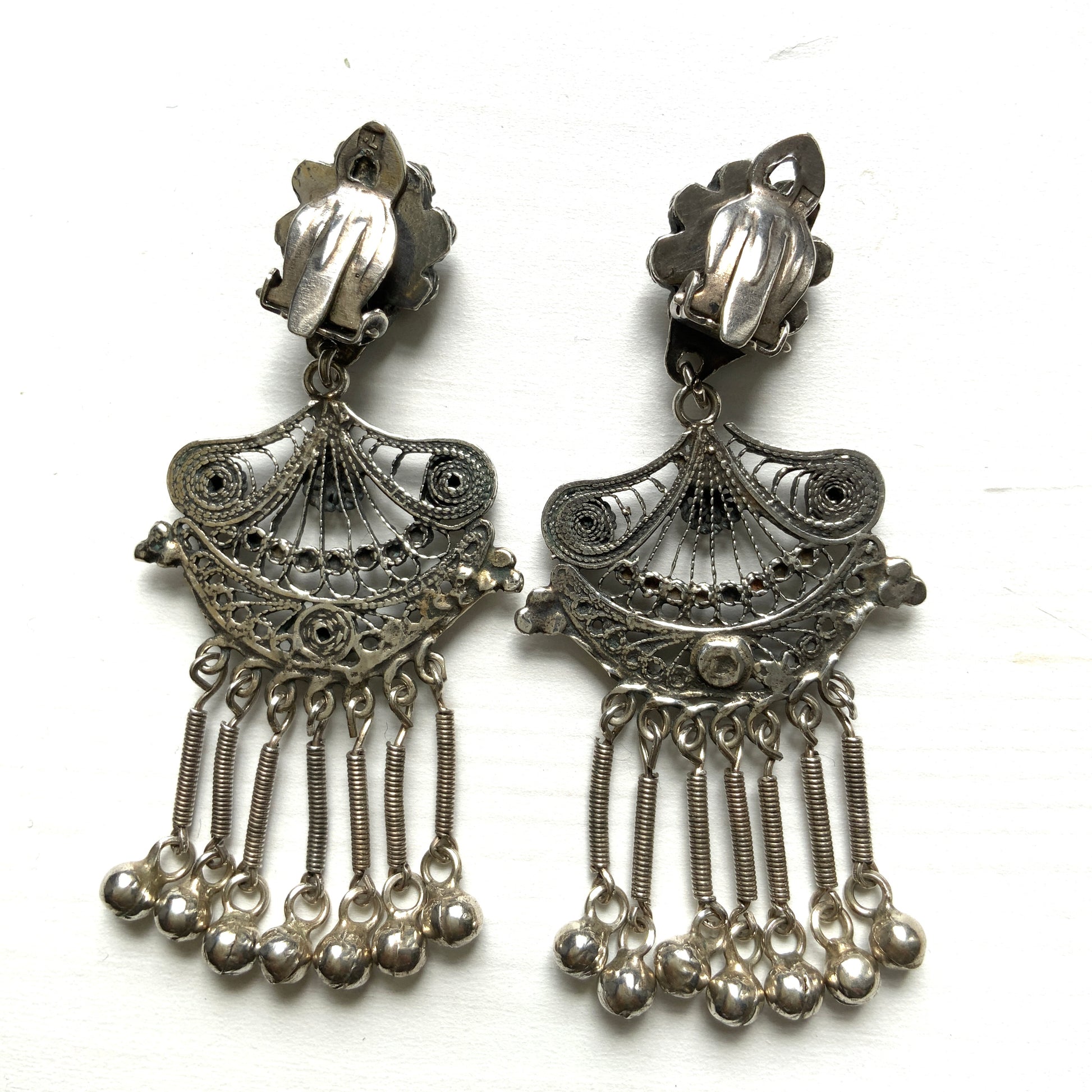 Silver filigree chandelier clip-on earrings with floral motifs and delicate openwork details.  シルバーのフィリグリー細工が施されたシャンデリア型クリップイヤリング。 