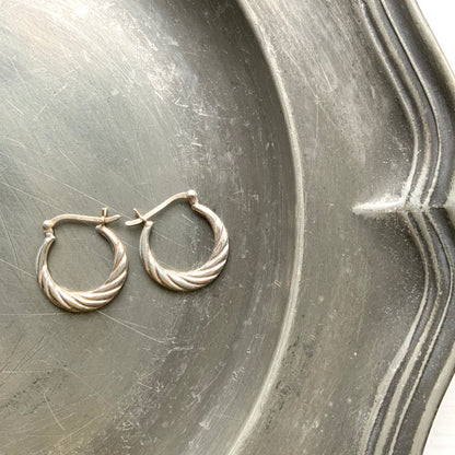 Silver hoop earrings with a twisted design.  シルバーのツイスト模様が入ったフープピアス。 