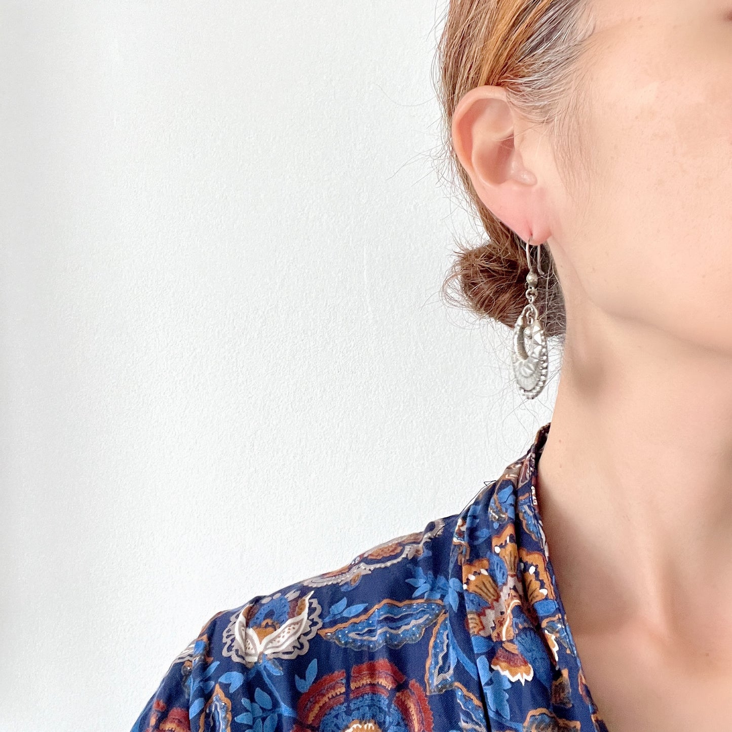 Striking silver tone hoop earrings with geometric embossed patterns and granulated bead details. 半月型にジオメトリックな打ち出し模様と粒状の装飾を施した、存在感あるシルバートーンのフープピアス。
