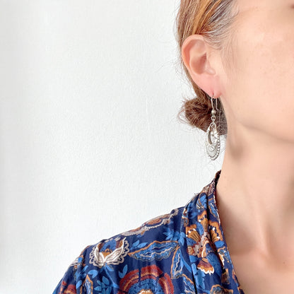 Striking silver tone hoop earrings with geometric embossed patterns and granulated bead details. 半月型にジオメトリックな打ち出し模様と粒状の装飾を施した、存在感あるシルバートーンのフープピアス。