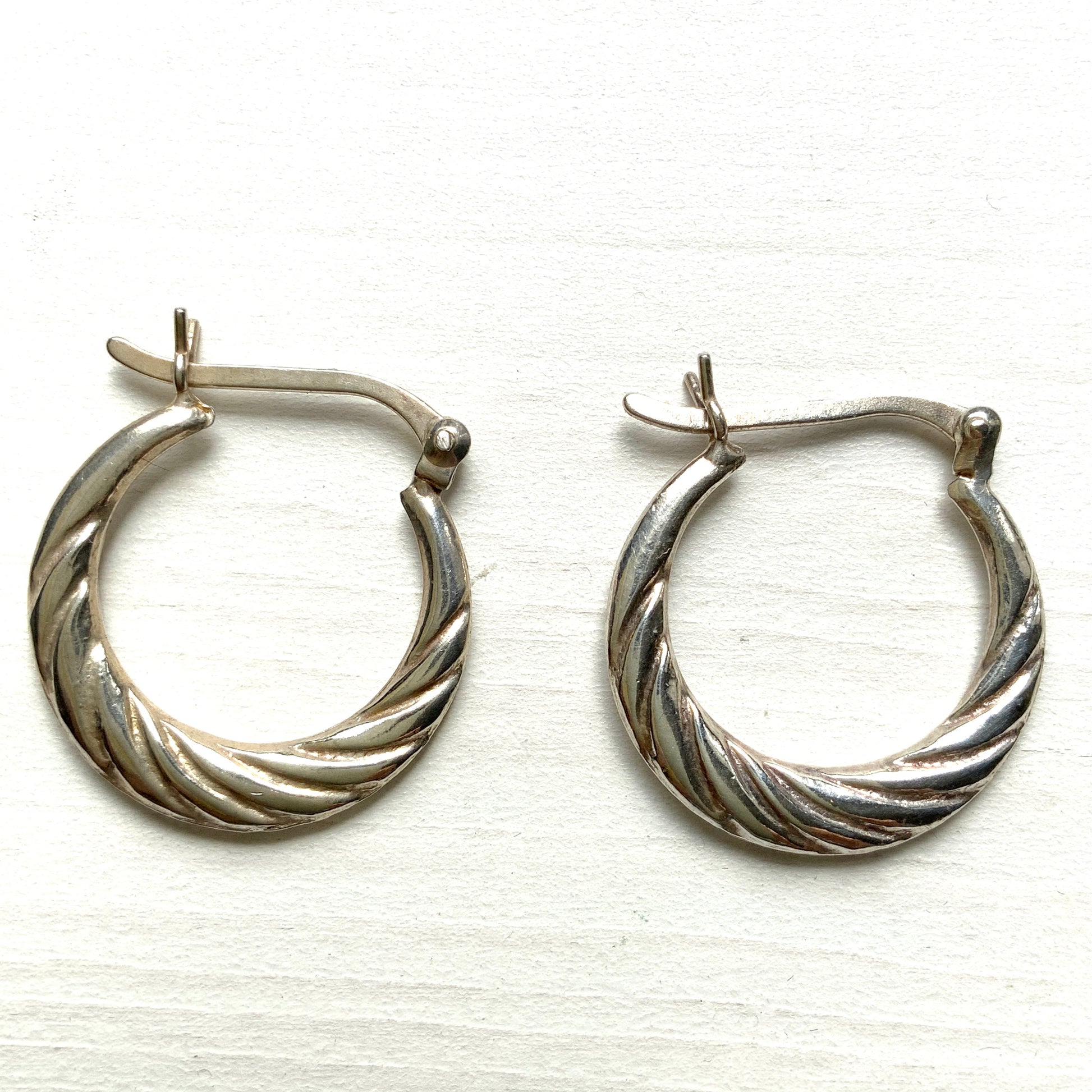 Silver hoop earrings with a twisted design.  シルバーのツイスト模様が入ったフープピアス。 