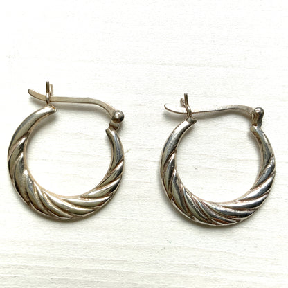 Silver hoop earrings with a twisted design.  シルバーのツイスト模様が入ったフープピアス。 