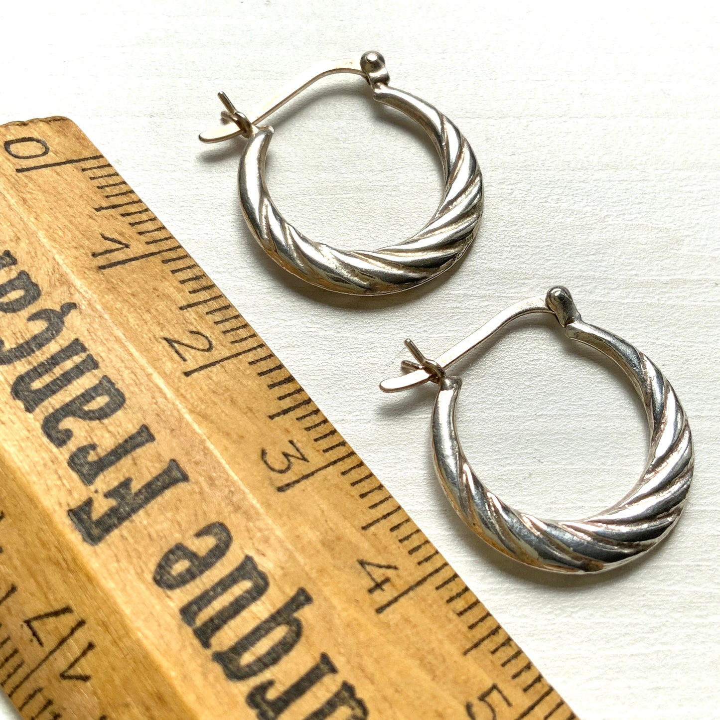 Silver hoop earrings with a twisted design.  シルバーのツイスト模様が入ったフープピアス。 