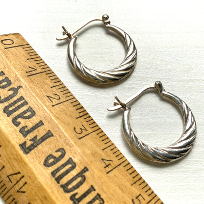 Silver hoop earrings with a twisted design.  シルバーのツイスト模様が入ったフープピアス。 