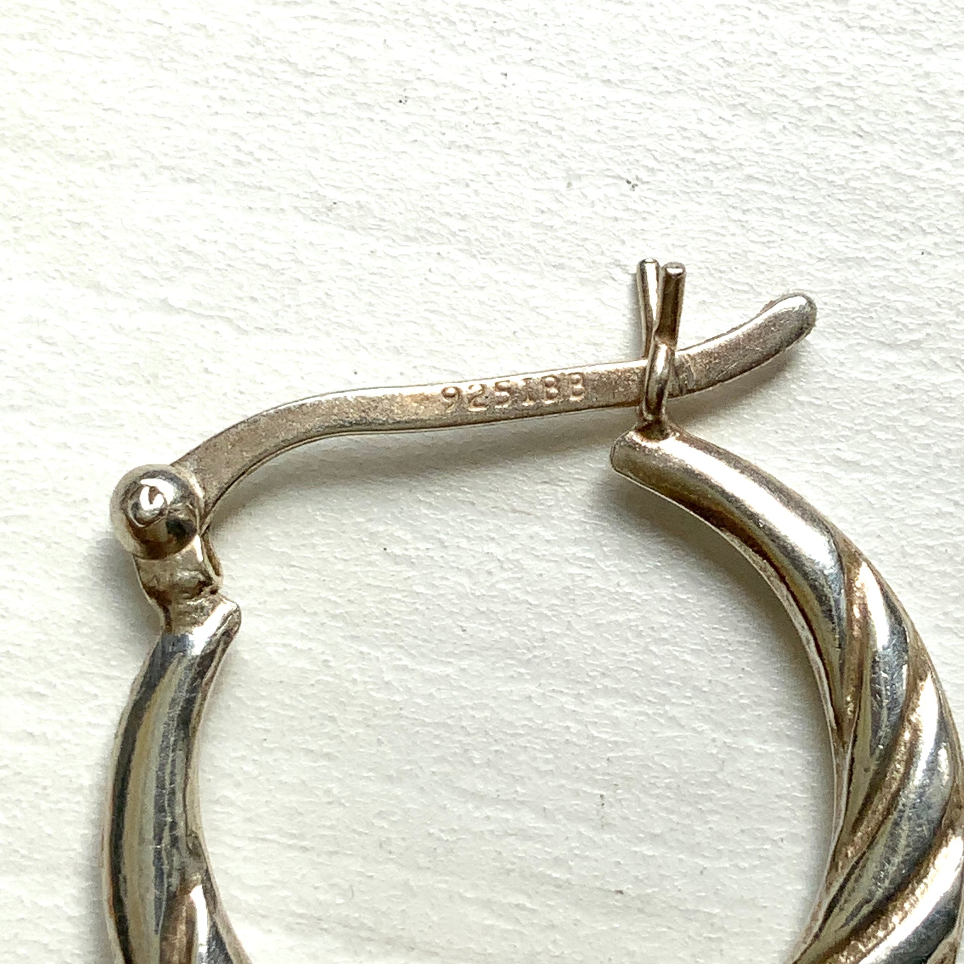 Silver hoop earrings with a twisted design.  シルバーのツイスト模様が入ったフープピアス。 