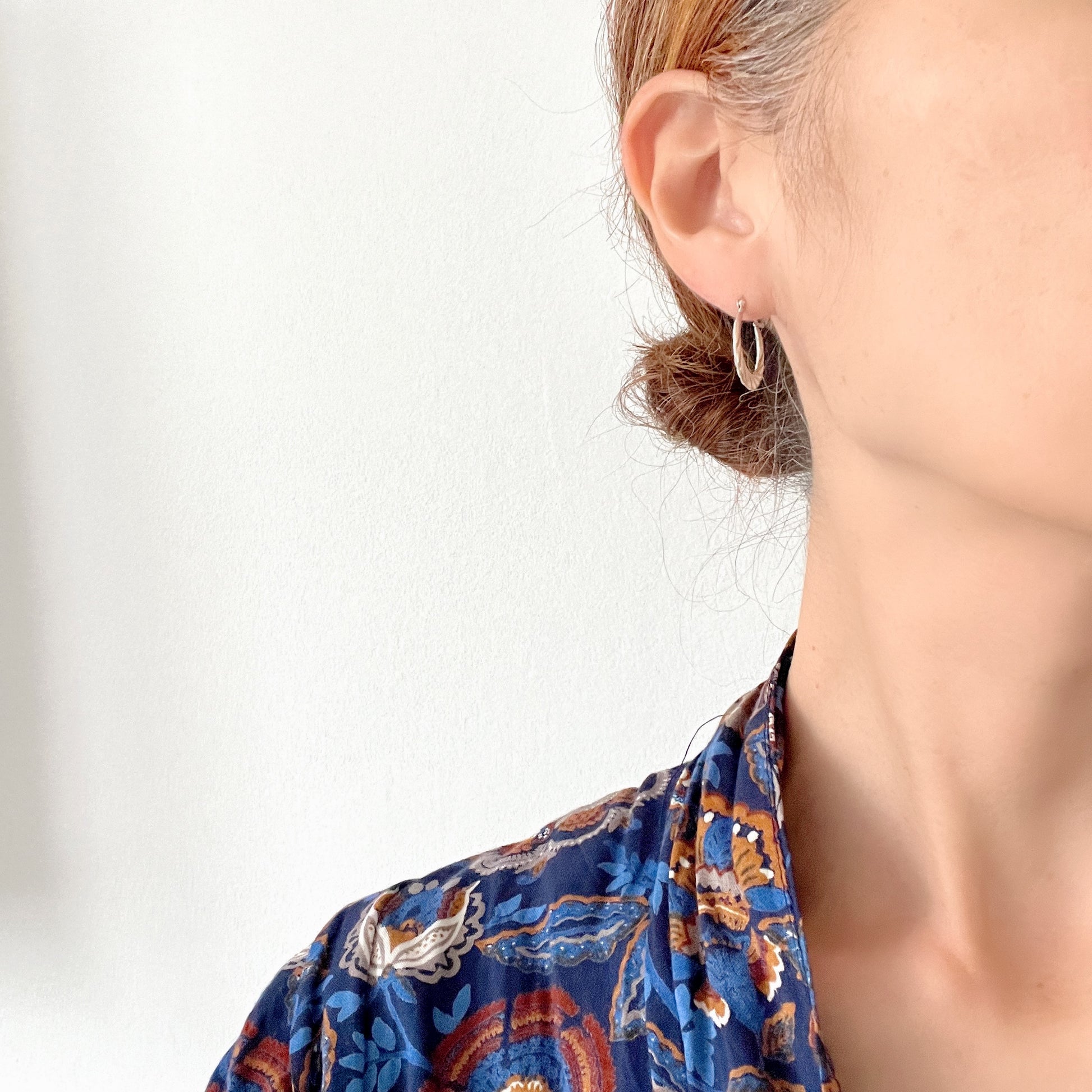 Silver hoop earrings with a twisted design.  シルバーのツイスト模様が入ったフープピアス。 