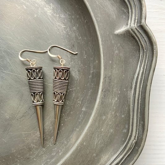 Silver spike-shaped earrings with tribal-inspired patterns.  トライバルな模様が入った細長いスパイク型のシルバーピアス。