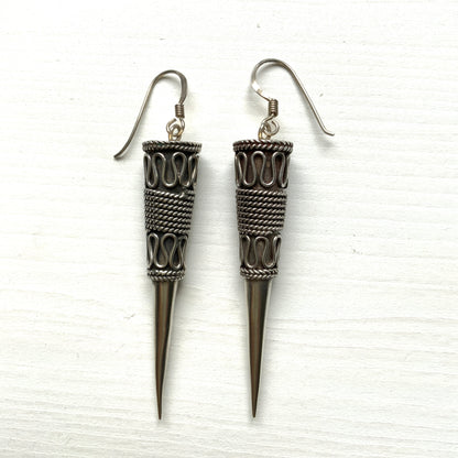 Silver spike-shaped earrings with tribal-inspired patterns.  トライバルな模様が入った細長いスパイク型のシルバーピアス。