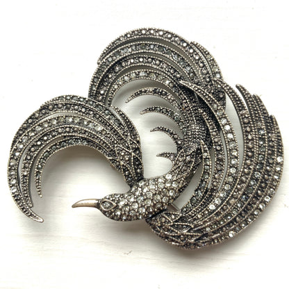 A vintage bird brooch in silver-tone metal, defined by its flowing, sculptural lines. 流れるようなラインが印象的な、鳥モチーフのブローチ。