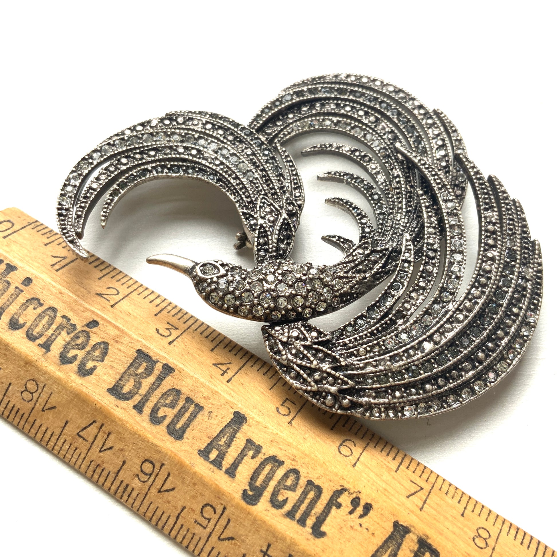 A vintage bird brooch in silver-tone metal, defined by its flowing, sculptural lines. 流れるようなラインが印象的な、鳥モチーフのブローチ。