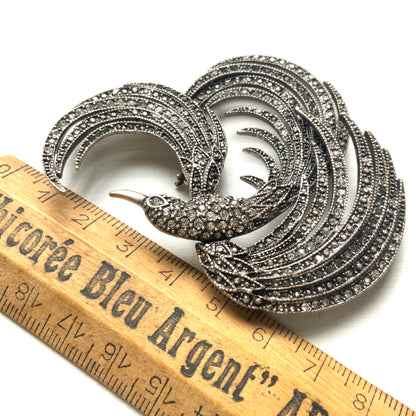 A vintage bird brooch in silver-tone metal, defined by its flowing, sculptural lines. 流れるようなラインが印象的な、鳥モチーフのブローチ。