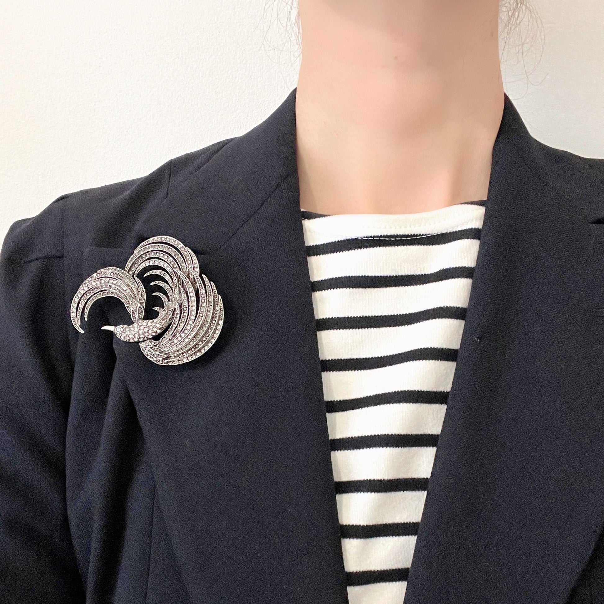 A vintage bird brooch in silver-tone metal, defined by its flowing, sculptural lines. 流れるようなラインが印象的な、鳥モチーフのブローチ。