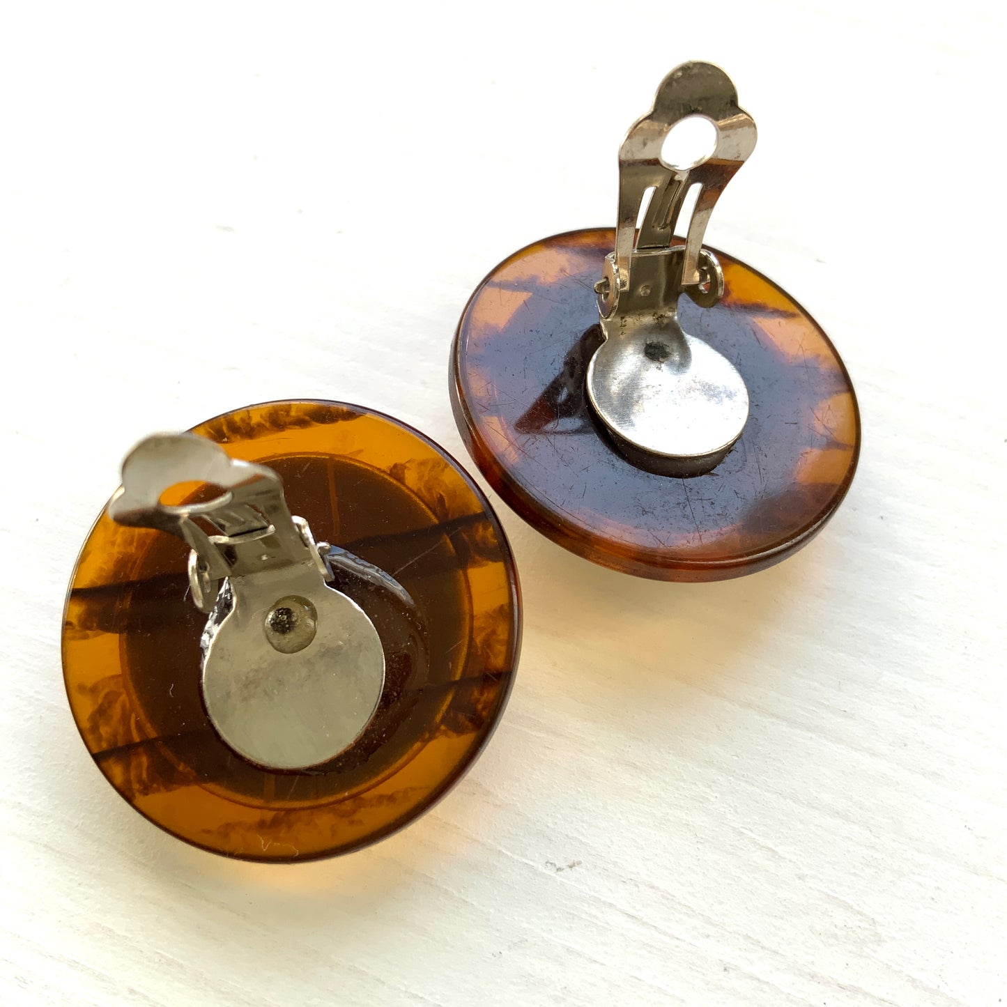 Dome-shaped clip-on earrings featuring a striking art pattern reminiscent of camouflage, framed in a faux tortoiseshell rim. べっ甲風の縁に、迷彩のようなアートパターンが印象的なドーム型イヤリング。