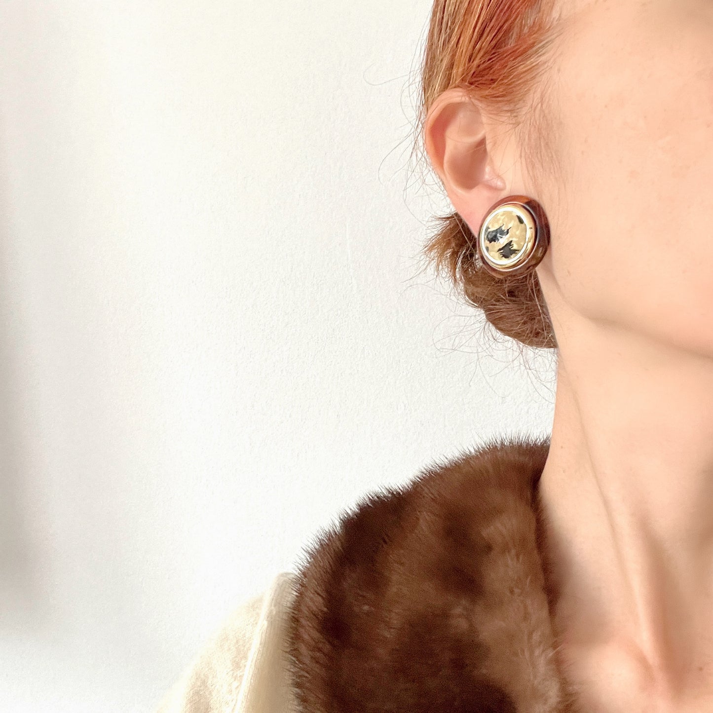 Dome-shaped clip-on earrings featuring a striking art pattern reminiscent of camouflage, framed in a faux tortoiseshell rim. べっ甲風の縁に、迷彩のようなアートパターンが印象的なドーム型イヤリング。