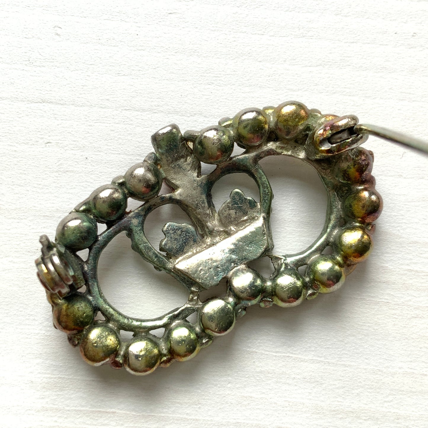 A brooch featuring a crown encircled by tricolour rhinestones – red, clear and blue. 王冠の周りをトリコロールカラーのラインストーンが囲んだブローチ。