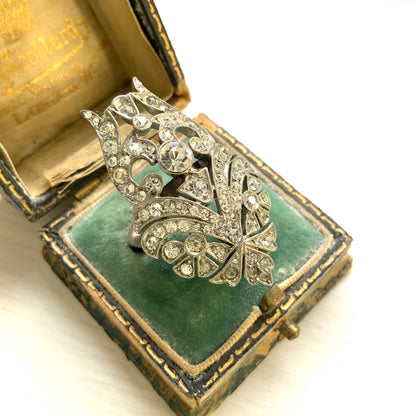 A striking vintage ring adorned with intricate scrollwork and densely set clear rhinestones. 細やかなスクロール装飾にクリアラインストーンがぎっしりと敷き詰められた、存在感たっぷりのヴィンテージリング。